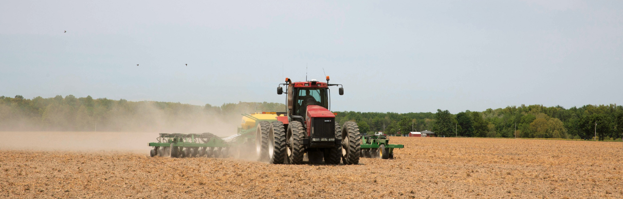 A farmer plants a field with a Case IH tractor and a John Deere planter.