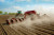A tractor planting in a dusty field