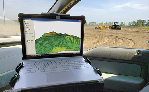 A farmer uses WM-Subsurface design software on a laptop in their vehicle.