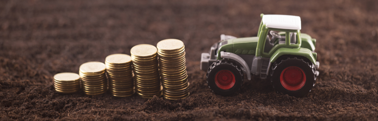A stock image of a toy tractor with coins.