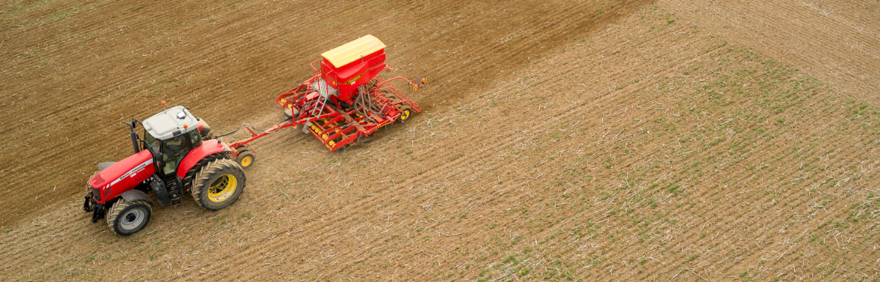 A red tractor planting an open field