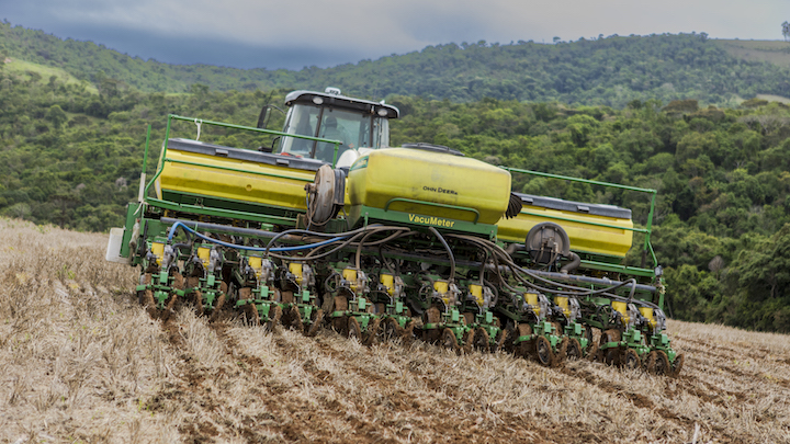 A farmer plants a field in rolling terrain with Trimble precision solutions.