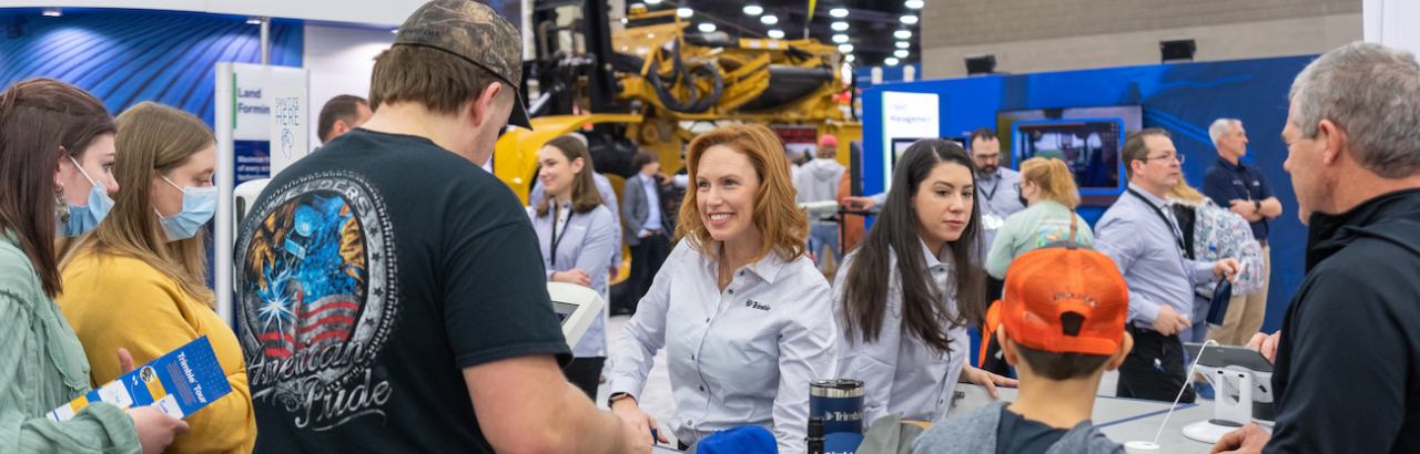 A group of Trimble employees talks to visitors at a tradeshow.