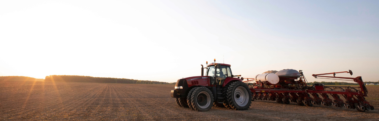 A Case IH tractor prepares for spring planting at sunrise.