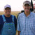 Los agricultores Fred y LeRoy Hofmann están de pie delante de su campo y su tractor.