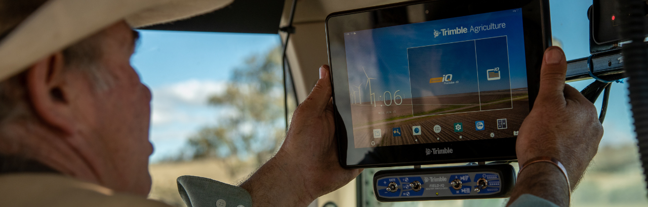 A farmer adjusts his Trimble GFX display, part of a connected precision solution.