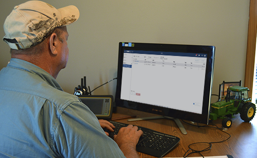 A farmer analyzes his farm data from the office using Trimble Ag Software.