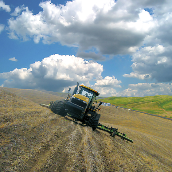 Ein Traktor auf einem hügeligen Feld, der zur Verbesserung der Genauigkeit das Geräteführungssystem TrueGuide von Trimble nutzt.