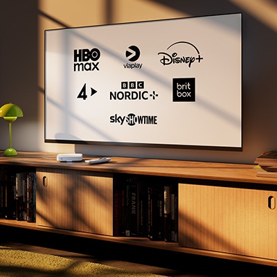 En TV på en träbänk visar logotyper för HBO Max, Viaplay, Disney+, TV4, BBC Nordic, Britbox och SkyShowtime.