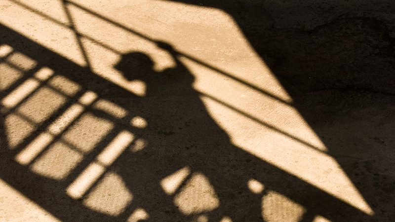 Skuggsilhuett av byggarbetare som går uppför trappa på byggställning. 