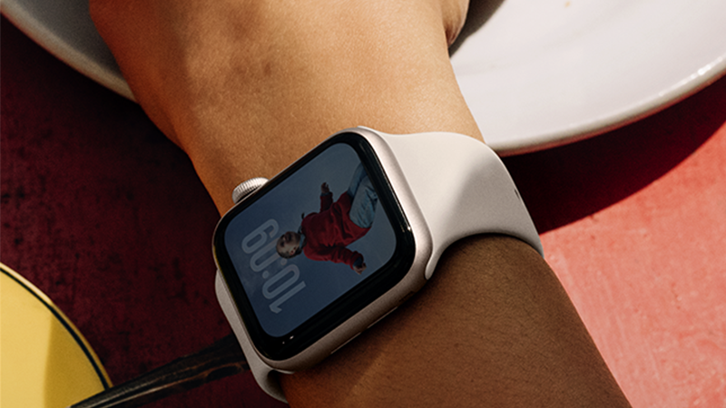 Vit Apple Watch på en handled som visar en digital urtavla.