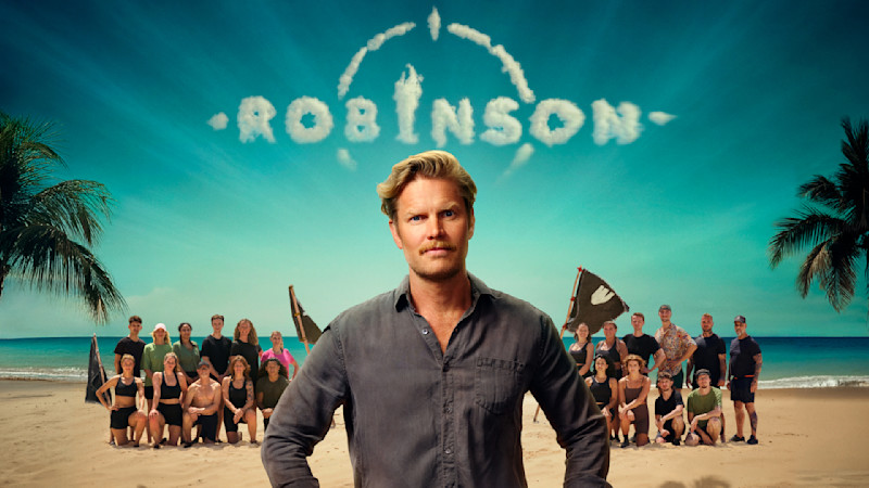 Programledare på strand med deltagare i bakgrunden, Robinson-logotyp av moln på turkosblå himmel över tropisk miljö.