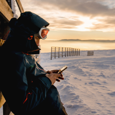 Kille i skidkläder tittar i sin mobil i fjällen