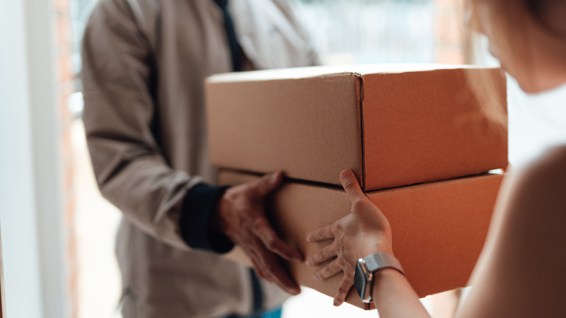 En person levererar två paket till en kvinna. 