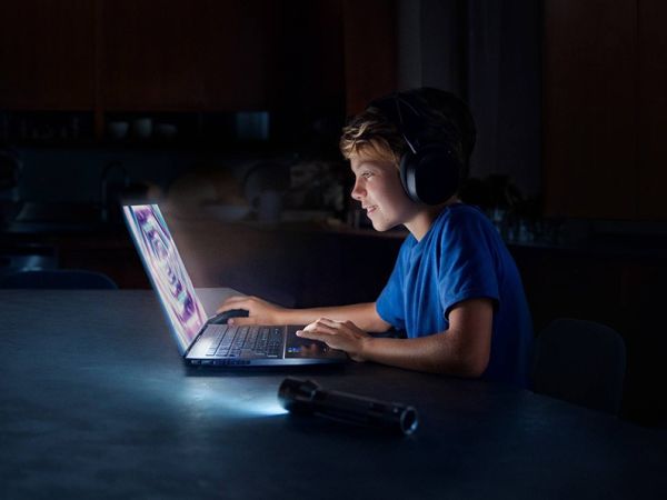 Pojke som sitter vid dator i mörker