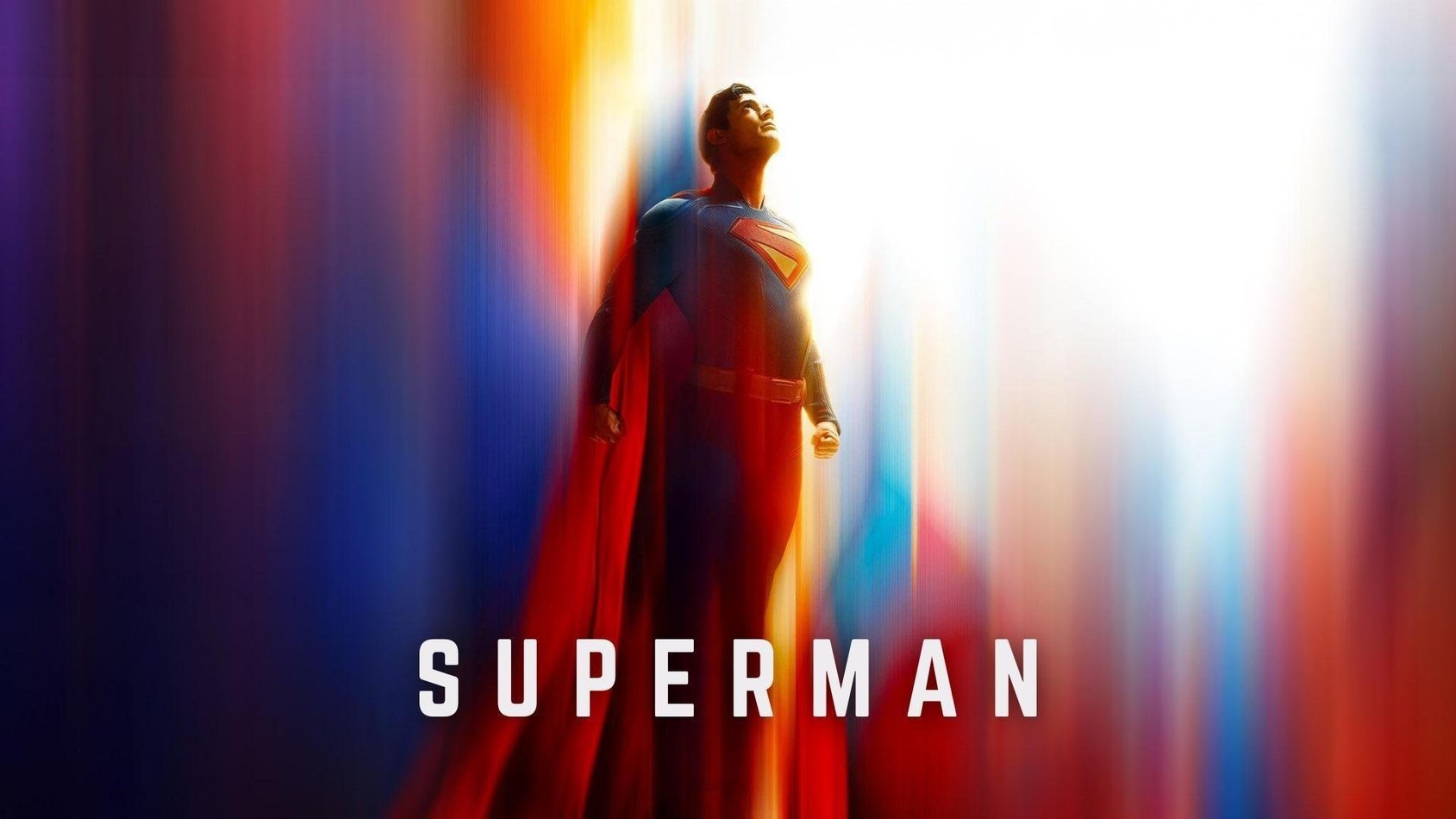 Superman i blå dräkt med röd cape tittar uppåt mot himlen mot en bakgrund av vibrerande färger.