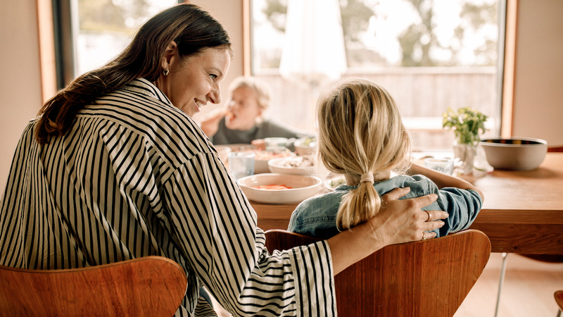 En kvinna och två barn vid ett frukostbord. 