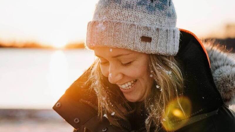 Närbild på leende kvinna med vinterkläder utomhus en solig vinterdag. 