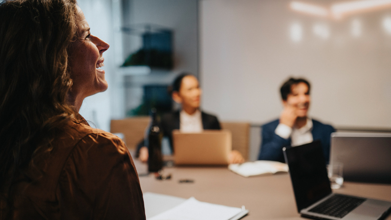 Tre kvinnor sitter vid ett konferensbord. På bordet syns papper och en laptop. 