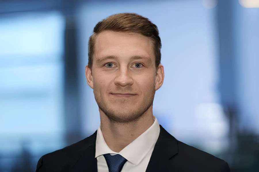 Johan Flink, Account Manager på Tele2 Företag. Han är klädd i mörk kavaj, blå slips och vit skjorta. Han småler och har brunt kort hår. I bakgrunden skymtar ett kontorslandskap i ljusa blå färgtoner. 