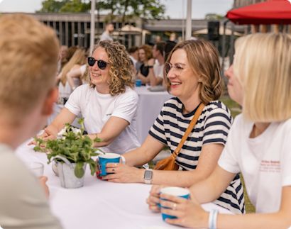 Careers_Finance_Hero Group of women sitting outside, smiling and having a conversation.