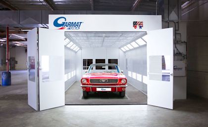 Red car inside a white Garmat USA spray booth with the front doors open