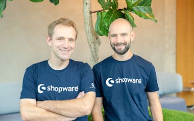 Stefan Hamann (left) and Sebastian Hamann (right) standing and smiling in the Shopware office.