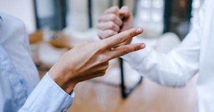 This image shows two people playing a game of rock-paper-scissors. One hand is showing the "scissors" gesture, while the other is in the "rock" position, suggesting a moment of decision or friendly competition.