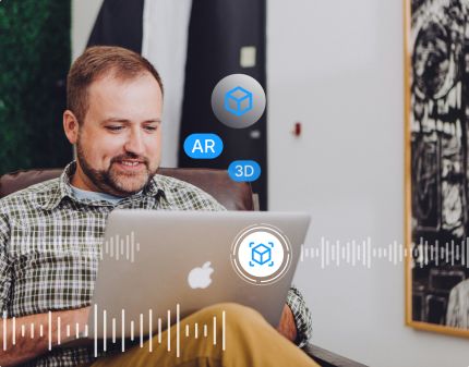 A man is sitting on a chair using a laptop, with virtual icons floating around him. These include symbols for AR, 3D, and a cube representing 3D modeling or AR content. The background features an office setting with artwork on the wall, and a soundwave pattern spans the bottom of the image.