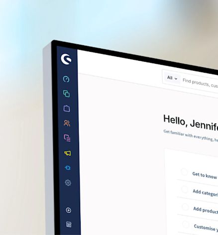 Partial view of the Shopware admin interface on a monitor, showing the side navigation and a welcome screen.