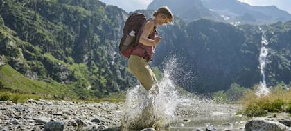 Woman in a valley, jumping in a shallow river
