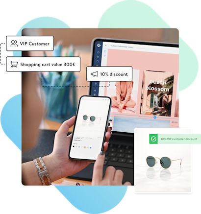 keyvisual-rulebuilder A person using a smartphone to browse an online store with sunglasses displayed. The screen shows a product page, while a laptop in the background has the same store's homepage open. Text bubbles point out that the user is a "VIP Customer," has a "Shopping cart value 300€," and is eligible for a "10% discount." A small image of sunglasses is displayed with a "10% VIP customer discount" label. The background contains soft abstract shapes in blue and green tones.