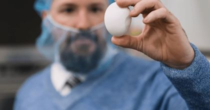 Man in food-protective clothing holding an egg