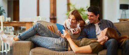 Family lounging on a sofa looking at an ipad