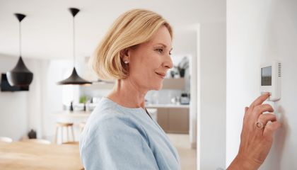 Woman regulating a thermostat on the wall of a modern kitchen