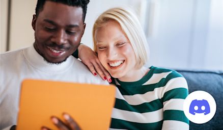 Two people look at their tablet and laughing.