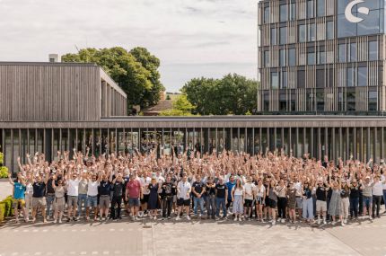 Tutti i dipendenti di Shopware in piedi nel campus, applaudono e alzano le mani in aria.