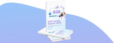 Rendering 3D di un libro intitolato "B2B Trends Report 2024" di Shopware. La copertina include icone legate al mondo degli affari e l'immagine di due persone che discutono. Un libro è in piedi e un altro è appoggiato su uno sfondo blu sfumato.