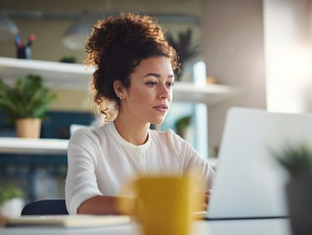 A woman at work working at a laptop and looking concentrated.