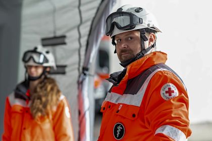 Man and woman in orange high-visibility jackets and protective headgear looking at the camera