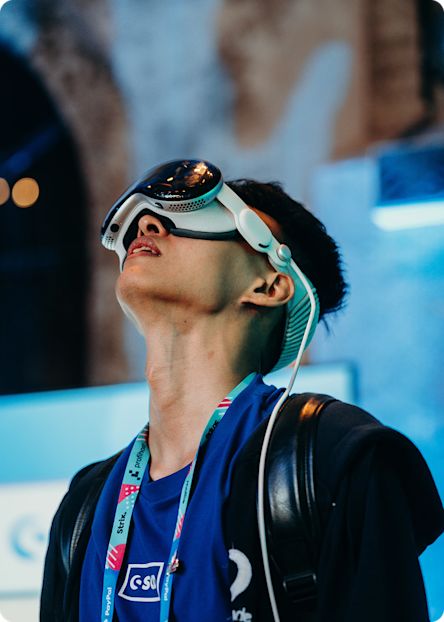 A person wearing a VR headset looks upward while testing an immersive experience at an event.