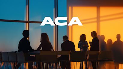 A group of business people at a desk in shadow standing by a window. 