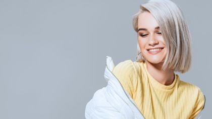 Woman smiling in a yellow shirt and white coat