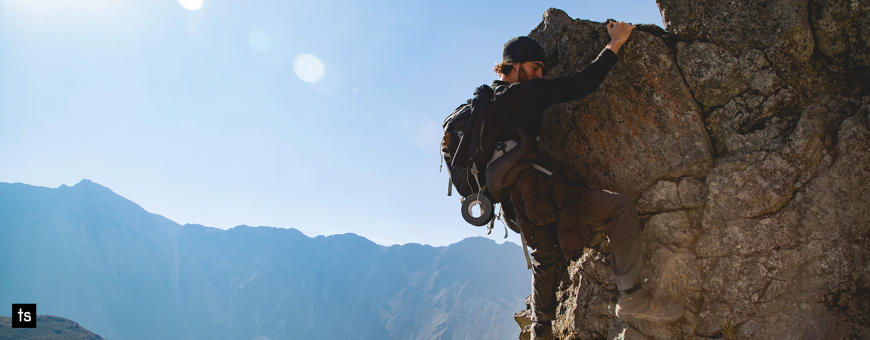 Young man rock climbing on a sunny day with a clear blue sky