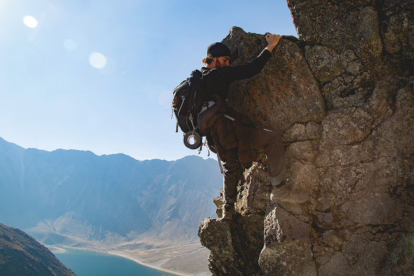 Young man rock climbing on a sunny day with a clear blue sky