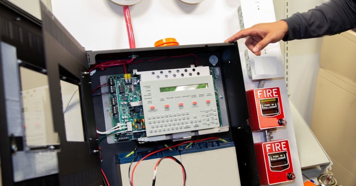 A case is attached to a wall, and within that case are some electronics with a display screen.