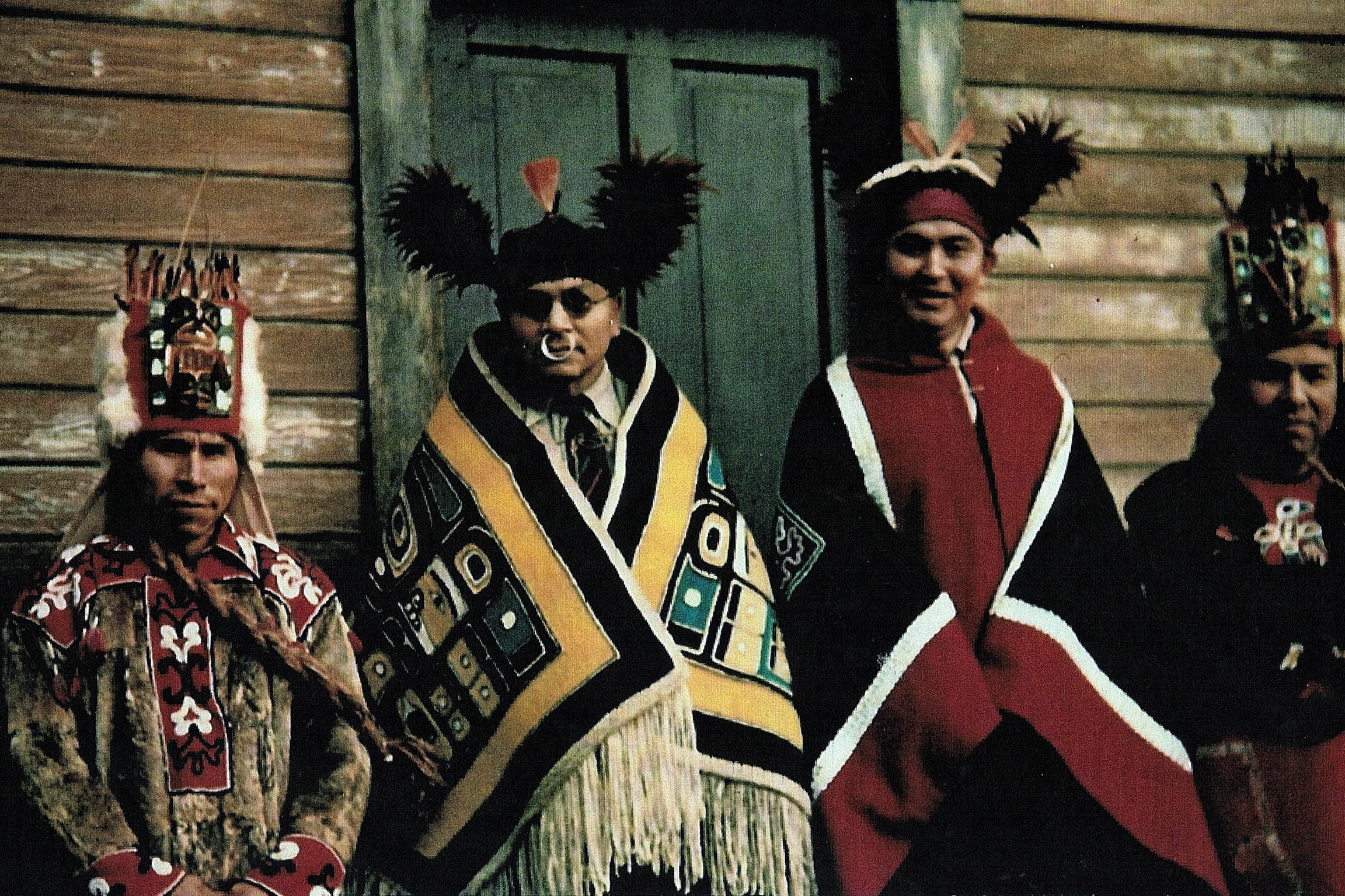 Four Indigenous Alaskan men dressed in ceremonial clothing and headresses