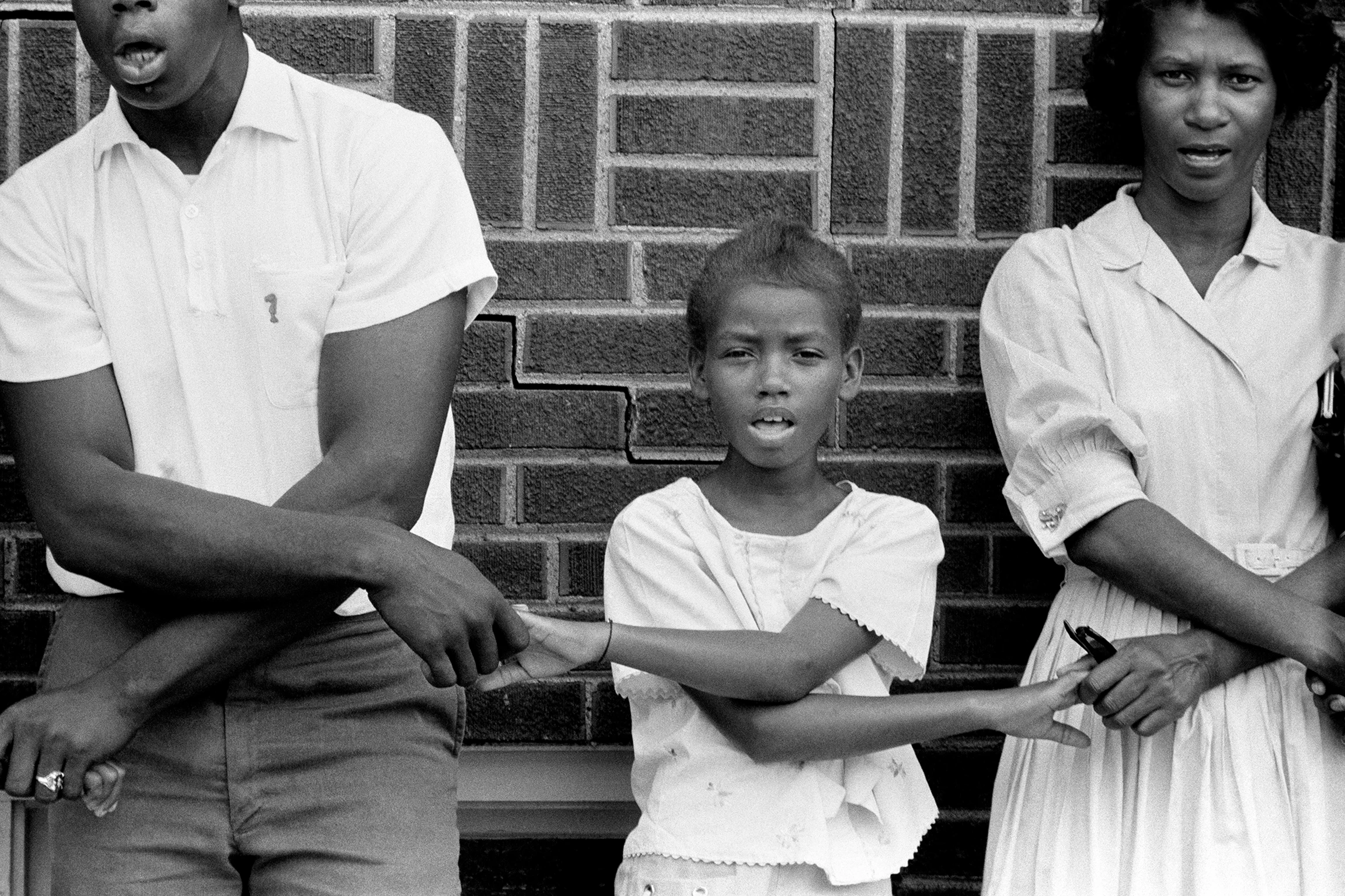 In black and white, three demonstrators from the Student Nonviolent Coordinating Committee stand together, holding hands