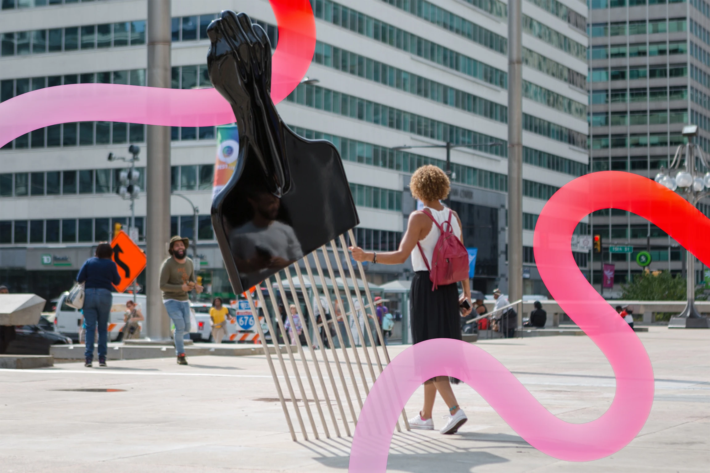On a plaza in an urban setting, a large piece of public art is an oversized hair pick