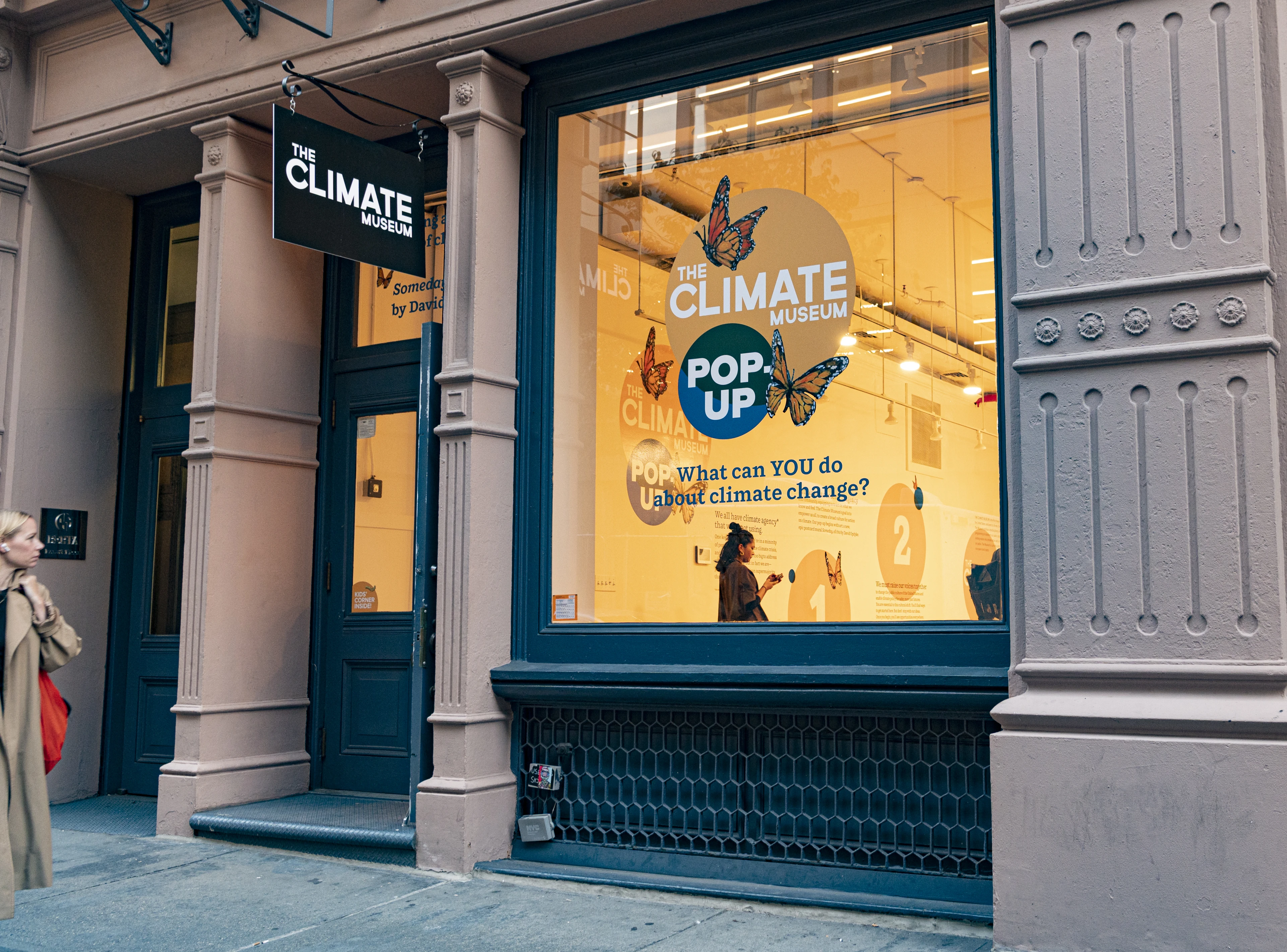 A view of a storefront space. The sign on the glass reads, "Climate Museum Pop-up"